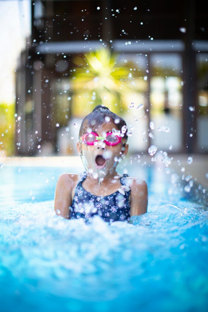 Mädchen mit Schwimmbrille lacht im Wasser